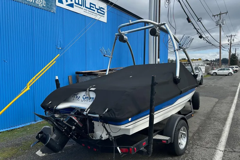 Slide: The Image of 1995 Reinell 18 BRXL boat on trailer, covered, parked by blue building. - 4