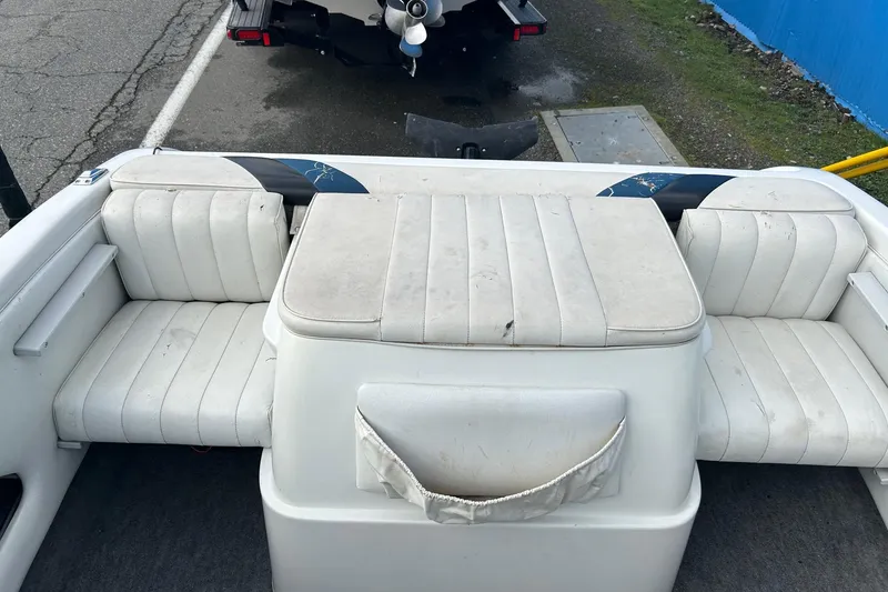 Slide: The Image of 1995 Reinell 18 BRXL boat interior with white cushioned seating and storage compartment. - 8