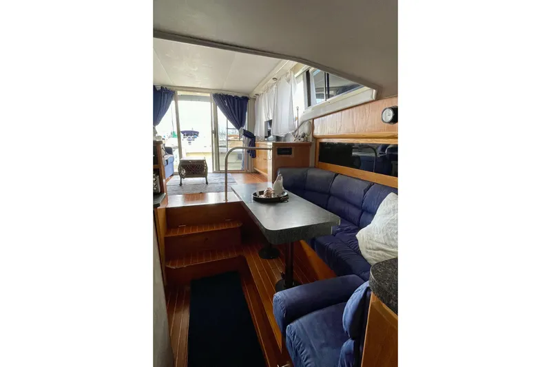 Slide: The Image of 1989 Silverton 34 Convertible yacht interior with blue seating, wooden flooring, and large windows. - 17