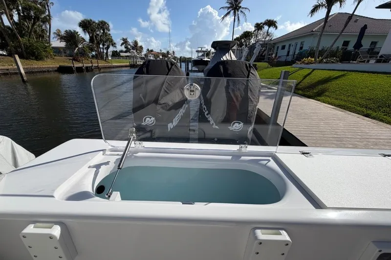 Slide: The Image of 2022 Bluewater 2850 CC boat docked with covered engines, surrounded by palm trees. - 2