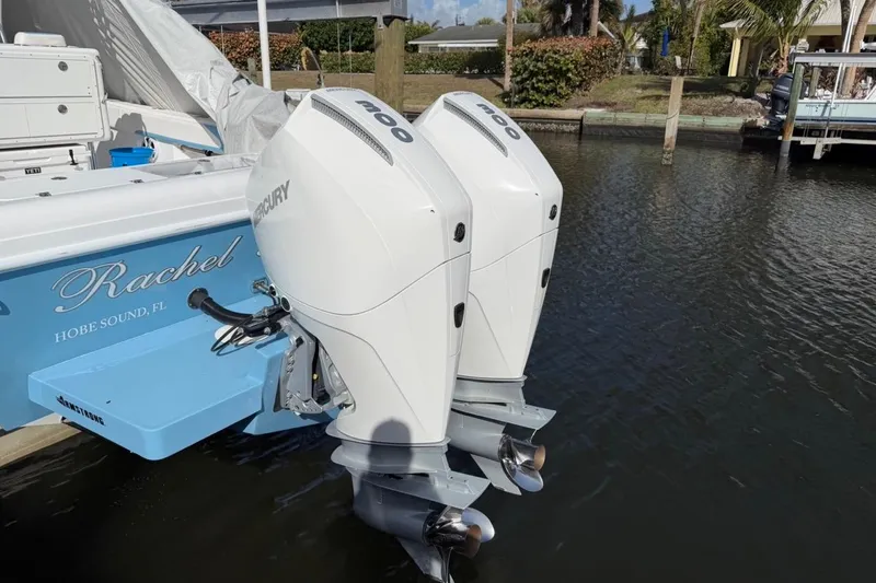 Slide: The Image of Twin Mercury outboard engines on a 2022 Bluewater 2850 CC boat docked by palm trees. - 21