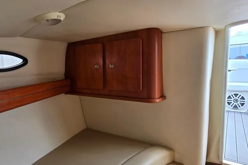 Slide: The Image of 2006 Rinker 246 Captiva Cuddy cabin interior with wooden storage and porthole. - 10