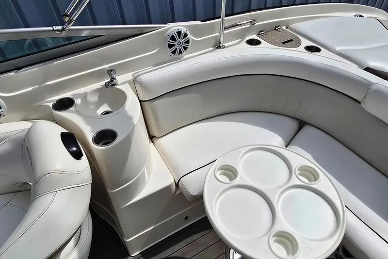 Slide: The Image of 2006 Rinker 246 Captiva Cuddy interior with white seating, cup holders, and a small sink. - 17