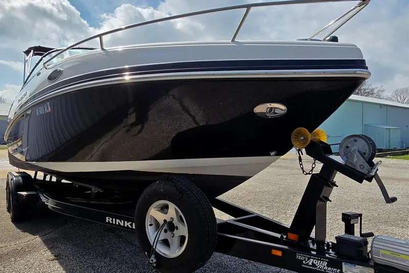 Slide: The Image of 2006 Rinker 246 Captiva Cuddy boat on trailer, parked outdoors under cloudy sky. - 24