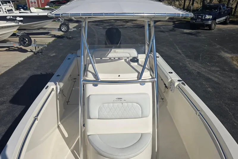 Slide: The Image of 2022 Cobia 237 Center Console boat with T-top and seating, parked on pavement. - 12