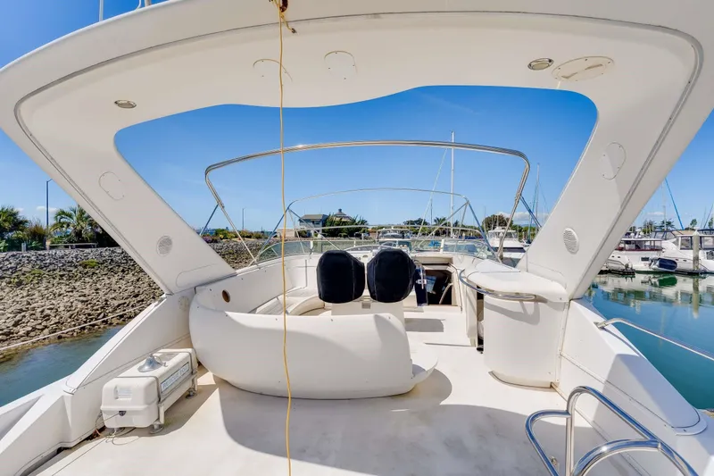 Slide: The Image of 1998 Bayliner 5788 Pilot House Motoryacht deck with seating, docked in marina under clear sky. - 111