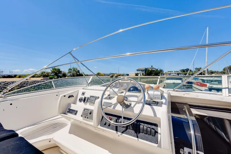 Slide: The Image of 1998 Bayliner 5788 Pilot House Motoryacht helm with steering wheel and controls, docked in marina. - 113
