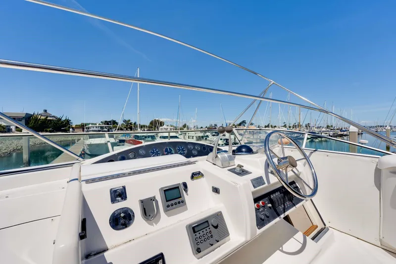 Slide: The Image of 1998 Bayliner 5788 Pilot House Motoryacht helm with marina view, showcasing controls and steering wheel. - 114