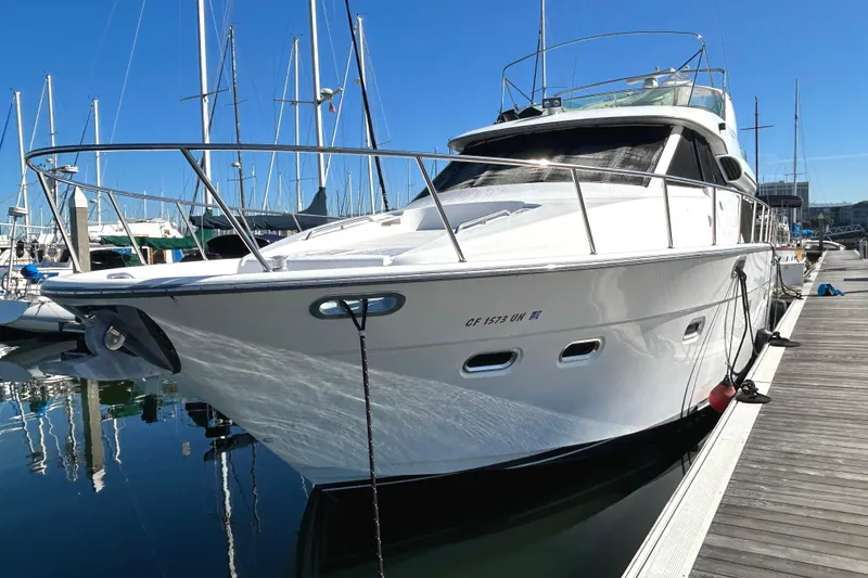 Slide: The Image of 1998 Bayliner 5788 Pilot House Motoryacht docked at marina under clear blue sky. - 2