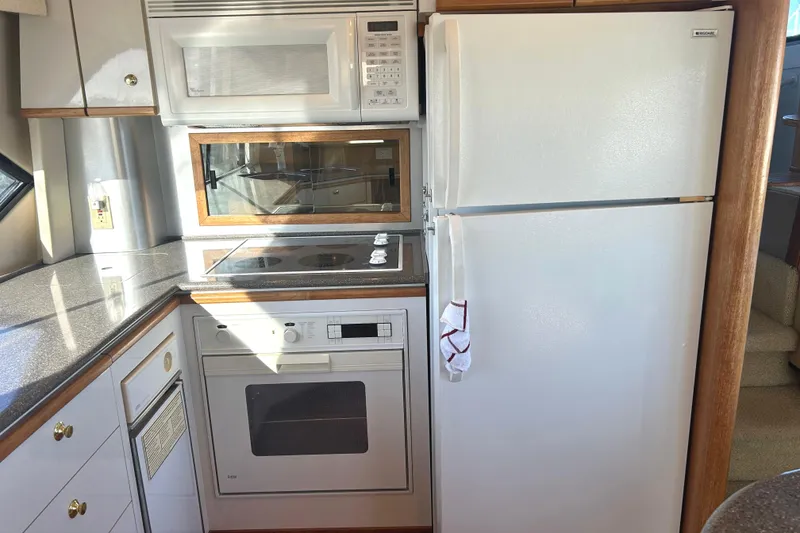 Slide: The Image of 1998 Bayliner 5788 Pilot House Motoryacht kitchen with stove and oven, featuring sleek countertops. - 25