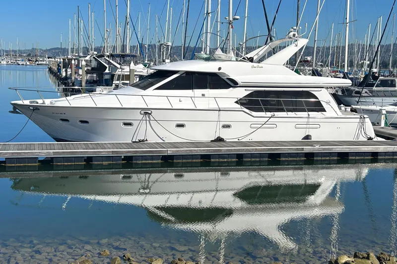 Slide: The Image of 1998 Bayliner 5788 Pilot House Motoryacht docked in a marina, reflecting on calm water. - 3