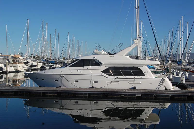 Slide: The Image of 1998 Bayliner 5788 Pilot House Motoryacht docked in a marina, reflecting on calm water. - 4