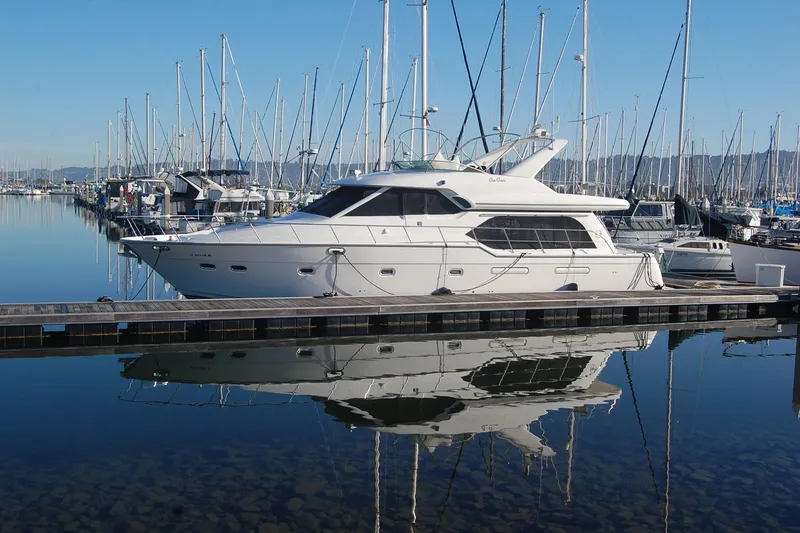 Slide: The Image of 1998 Bayliner 5788 Pilot House Motoryacht docked in a marina, reflecting on calm water. - 5