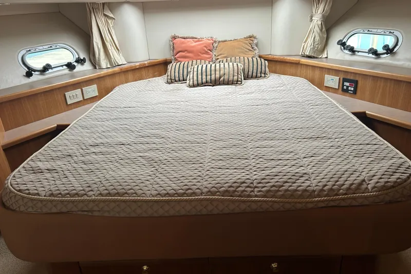Slide: The Image of 1998 Bayliner 5788 Pilot House Motoryacht bedroom with cozy bedding and porthole windows. - 56