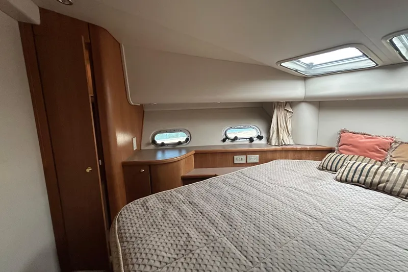 Slide: The Image of Cozy bedroom in 1998 Bayliner 5788 Pilot House Motoryacht with porthole windows and plush bedding. - 57