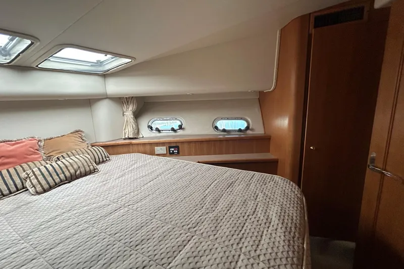Slide: The Image of 1998 Bayliner 5788 Pilot House Motoryacht bedroom with cozy bedding and porthole windows. - 58
