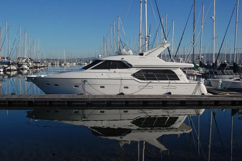Slide: The Image of 1998 Bayliner 5788 Pilot House Motoryacht docked in a marina, reflecting on calm water. - 6
