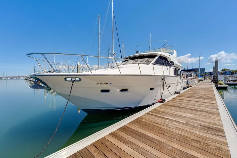 Slide: The Image of 1998 Bayliner 5788 Pilot House Motoryacht docked at marina under clear blue sky. - 82
