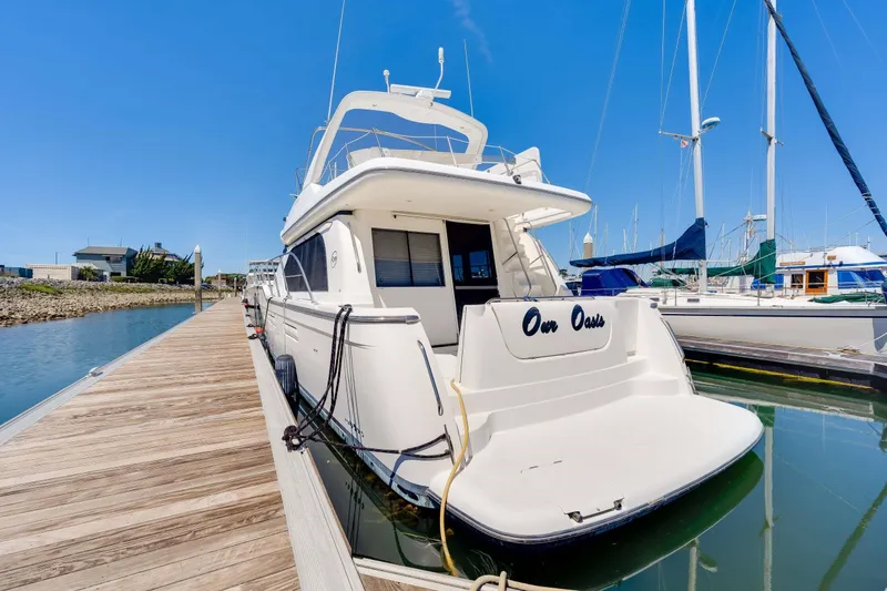 Slide: The Image of 1998 Bayliner 5788 Pilot House Motoryacht docked at marina under clear blue sky. - 83