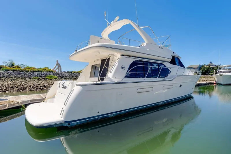 Slide: The Image of 1998 Bayliner 5788 Pilot House Motoryacht docked in a serene marina setting. - 85