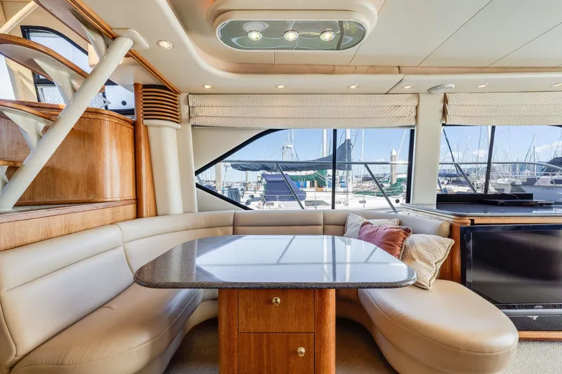 Slide: The Image of Luxurious interior of 1998 Bayliner 5788 Pilot House Motoryacht with elegant seating and marina view. - 90