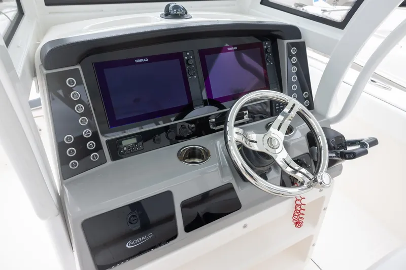 Slide: The Image of 2021 Robalo R272 Center Console helm with dual Simrad displays and stainless steel steering wheel. - 11