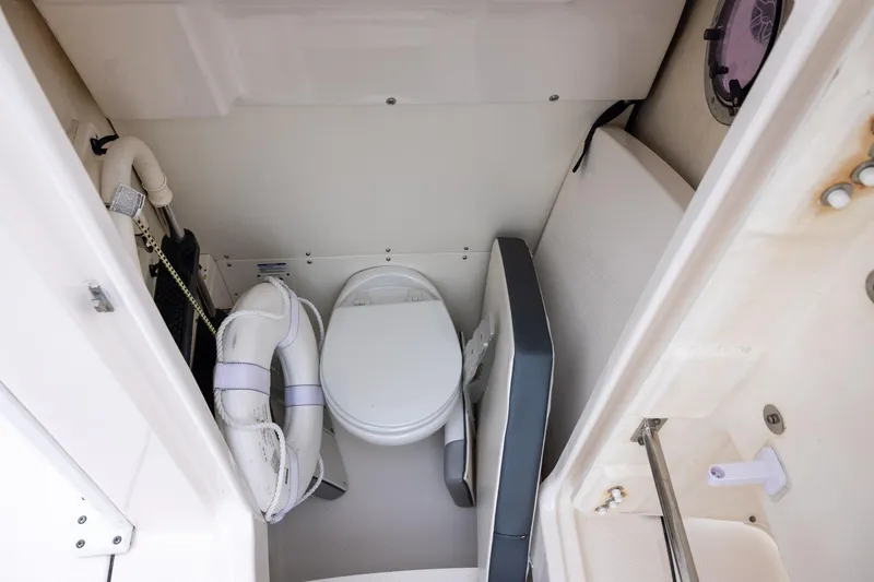 Slide: The Image of 2021 Robalo R272 Center Console boat interior with toilet and life preserver. - 18