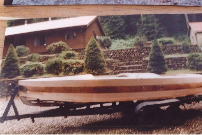 Slide: The Image of 1931 Dodge 16' Sea Nymph boat on trailer, rustic background with trees and house. - 16