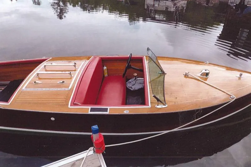 Slide: The Image of 1931 Dodge 16' Sea Nymph wooden boat with red interior, docked on calm water. - 3