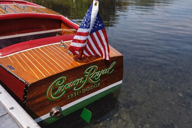 Slide: The Image of 1931 Dodge 16' Sea Nymph boat with American flag on water. - 6