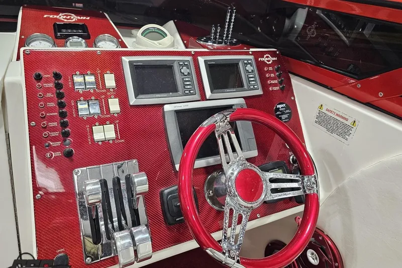 Slide: The Image of Dashboard of a 2009 Fountain 47 Lightning boat with red accents and navigation controls. - 82