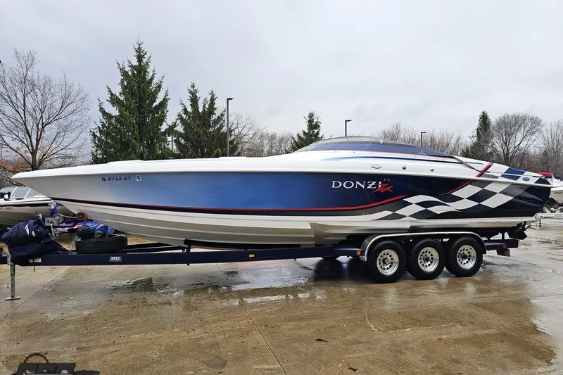 Slide: The Image of 2000 Donzi 33 ZX speedboat on trailer, blue and white design, parked outdoors. - 10