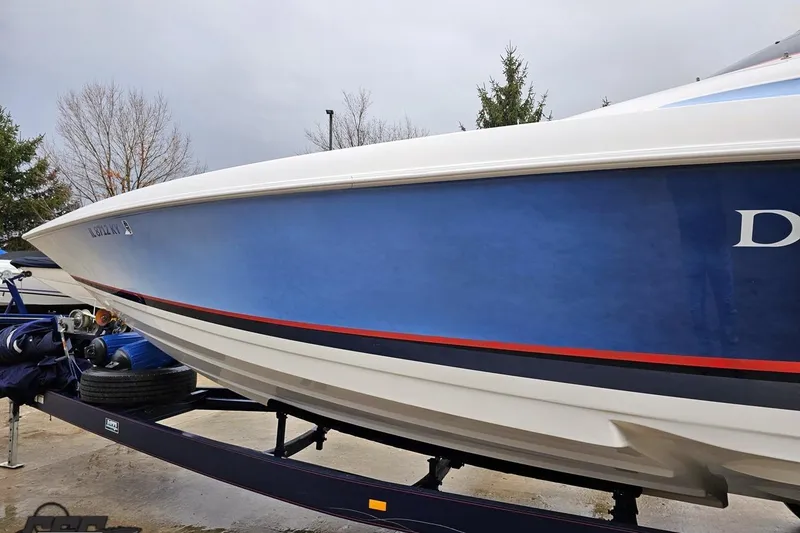 Slide: The Image of 2000 Donzi 33 ZX boat on trailer, blue hull with red stripe, parked outdoors. - 12