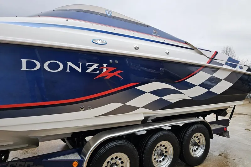 Slide: The Image of 2000 Donzi 33 ZX speedboat with blue and white checkered design on trailer. - 14