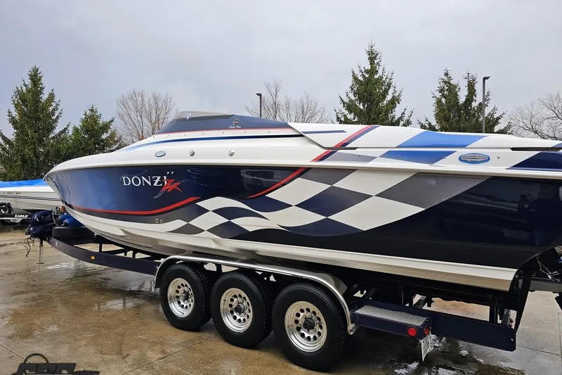 Slide: The Image of 2000 Donzi 33 ZX speedboat with checkered design on trailer, parked outdoors. - 16