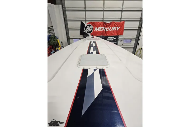 Slide: The Image of 2000 Donzi 33 ZX boat with sleek design and bold stripe, indoors with Mercury banner. - 57