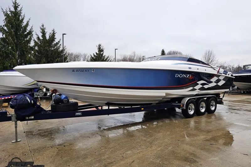 Slide: The Image of 2000 Donzi 33 ZX speedboat on trailer, blue and white design, parked outdoors. - 9