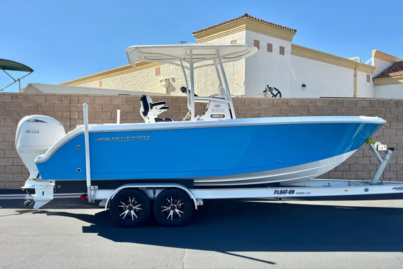 The Image of 2024 Aquasport 2200 Center Console boat on trailer, blue hull, Yamaha engine. - 0