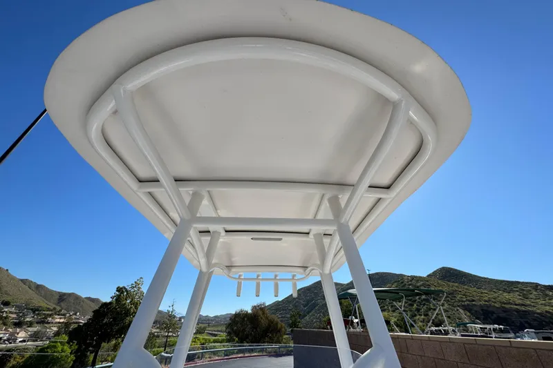 Slide: The Image of 2024 Aquasport 2200 Center Console T-top against clear blue sky and scenic hills. - 17