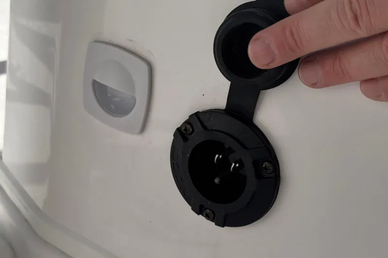 Slide: The Image of 2024 Aquasport 2200 Center Console power outlet with protective cover. - 23