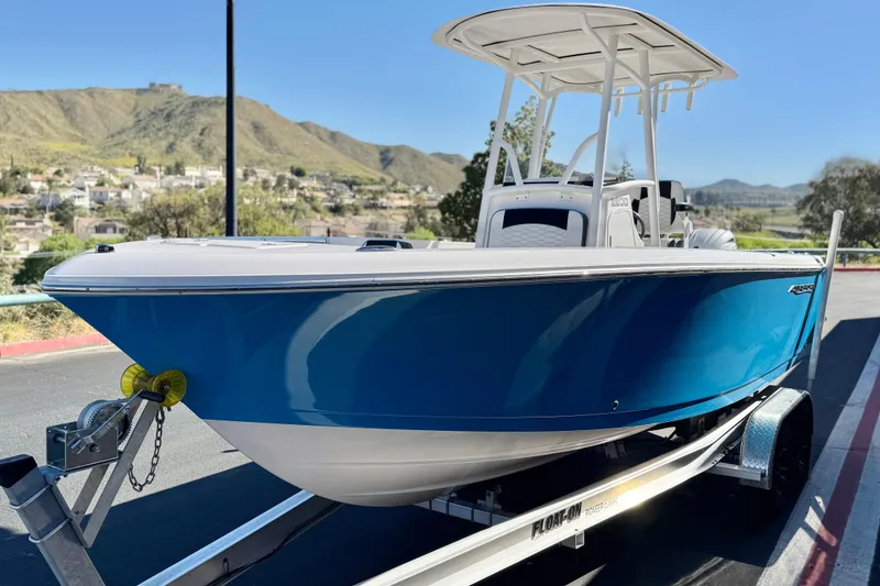 Slide: The Image of 2024 Aquasport 2200 Center Console boat on trailer, scenic mountain backdrop. - 3