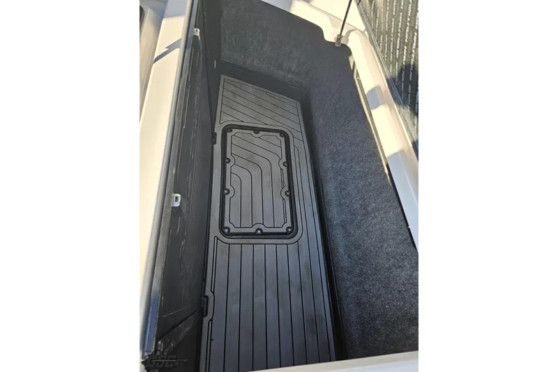 Slide: The Image of 2015 Nautique Super Air Nautique G23 storage compartment with black mat and carpeted sides. - 132