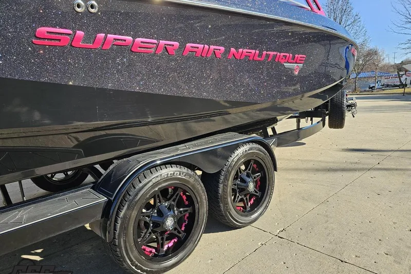 Slide: The Image of 2015 Nautique Super Air Nautique G23 boat on trailer, featuring sleek design and custom wheels. - 15