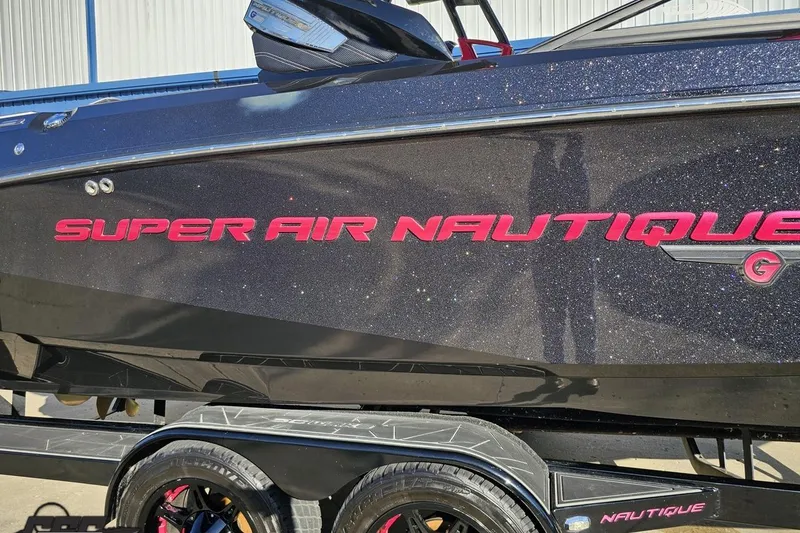 Slide: The Image of 2015 Nautique Super Air Nautique G23 boat with glittery black finish and red logo. - 9
