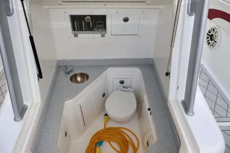 Slide: The Image of Interior of 2015 Deep Impact 33 boat featuring a compact bathroom with sink and toilet. - 11