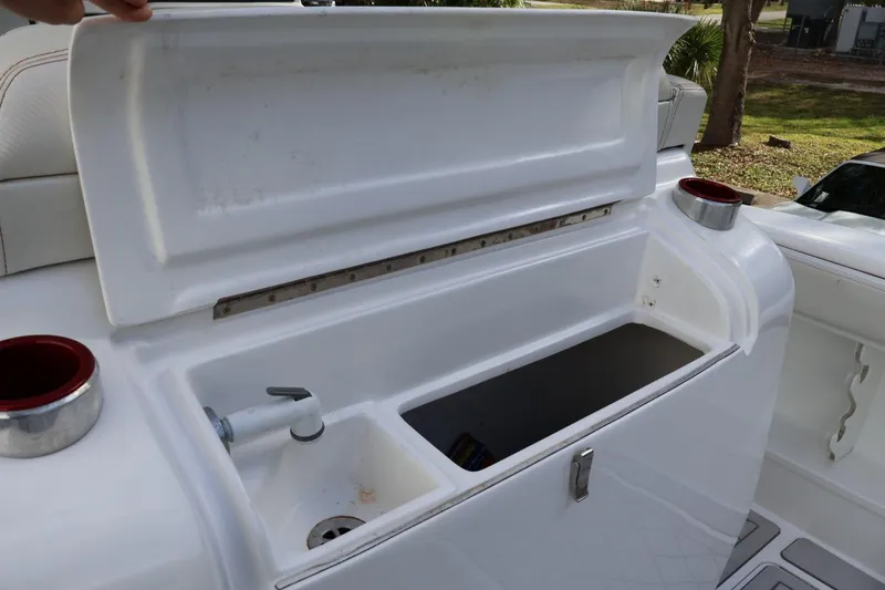 Slide: The Image of Open storage compartment on a 2015 Deep Impact 33 boat, featuring a sink and cup holders. - 6