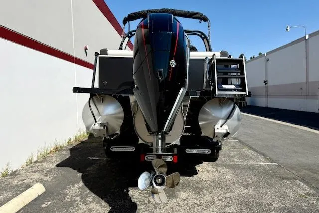 Slide: The Image of 2026 Avalon Catalina Quad Lounge 27' boat, rear view with dual propellers, parked outdoors. - 17