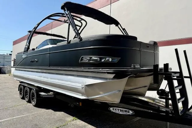 Slide: The Image of 2026 Avalon Catalina Quad Lounge 27' pontoon boat on trailer, sleek black design. - 2