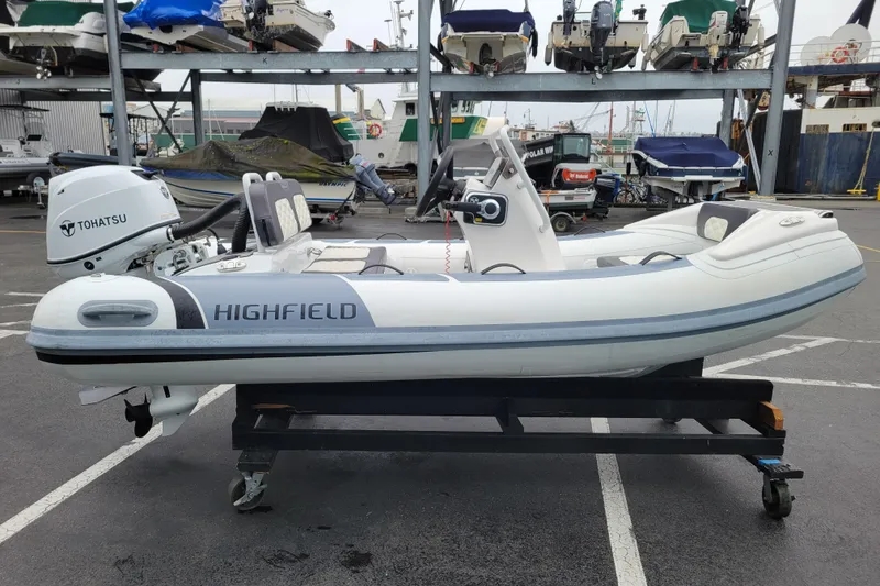 Slide: The Image of 2023 Highfield Sport 330 inflatable boat with Tohatsu engine on display at a marina. - 4