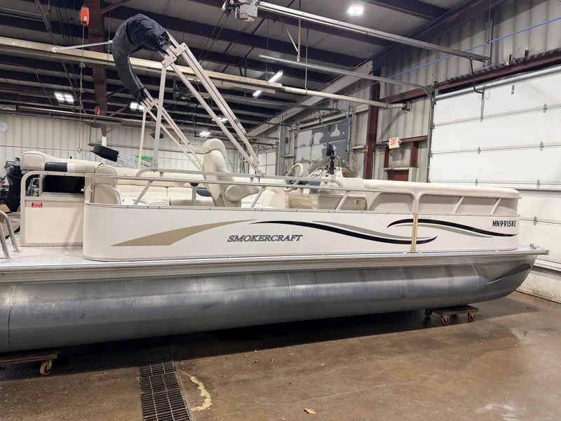 Slide: The Image of 2006 Smoker Craft pontoon boat in warehouse, side view. - 44